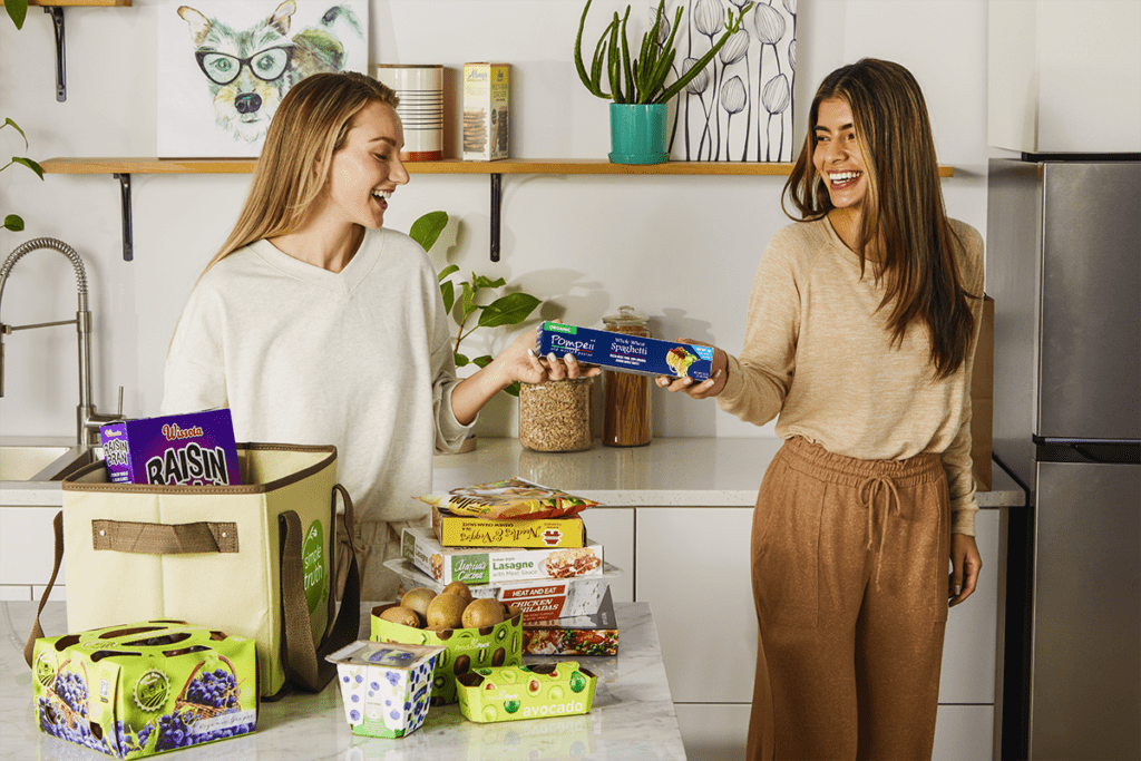 Zwei Frauen laden Lebensmittel von der Theke in den Kühlschrank